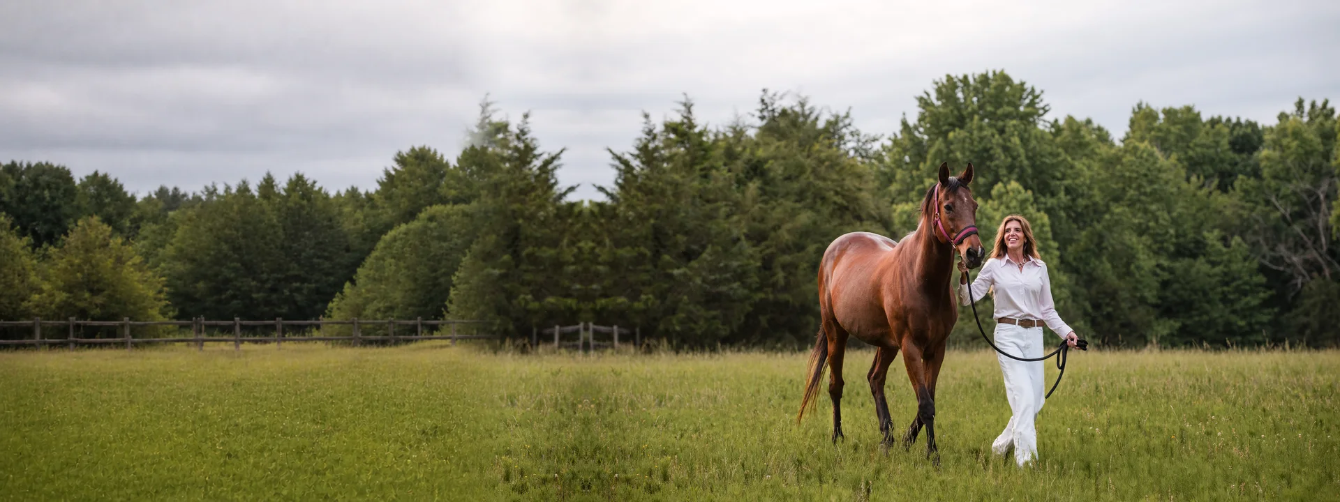 Denise Alala walking with her horse, Henry, through a meadow
