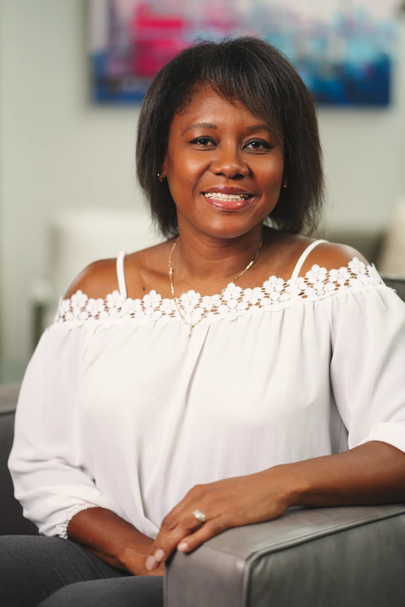 Woman in a white blouse seated against a light neutral interior