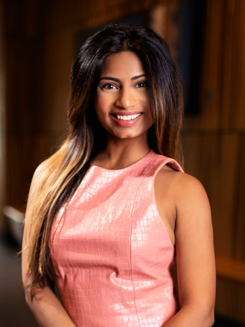 Woman in a coral dress photographed in a warm wood interior