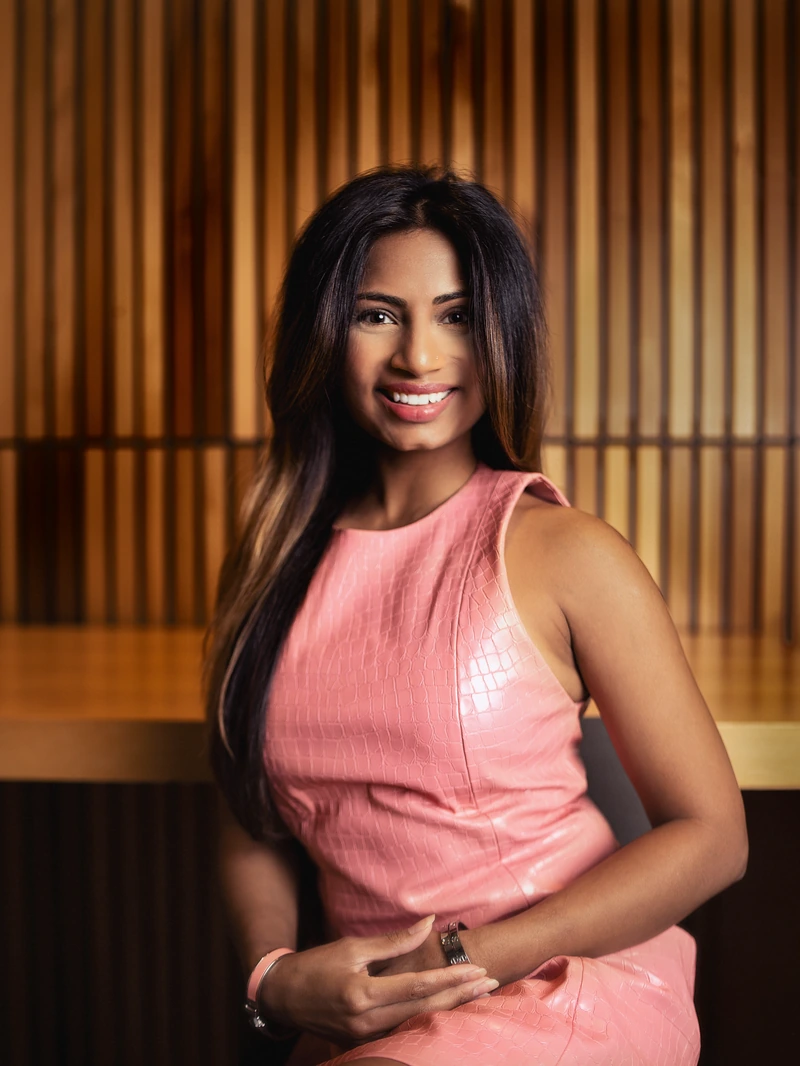 Woman in a coral dress photographed in a warm wood interior