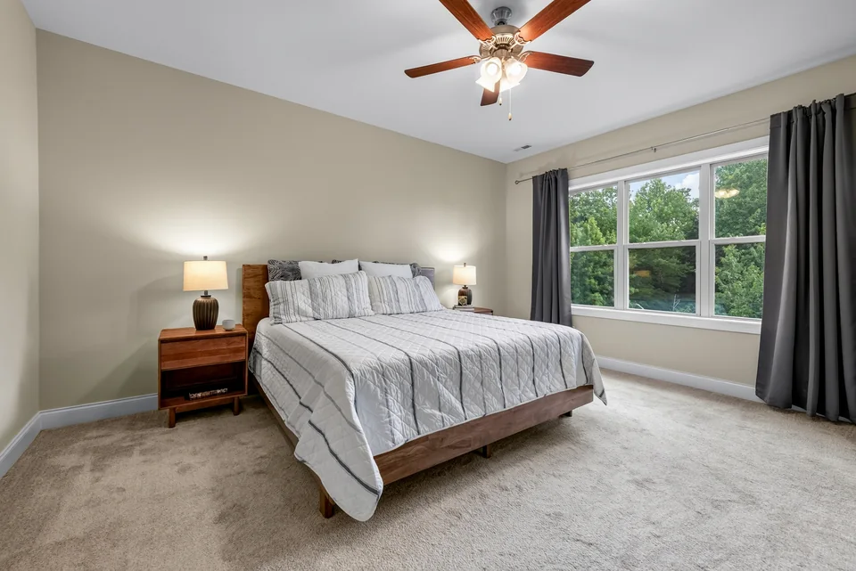 Bedroom with neutral carpet and two windows