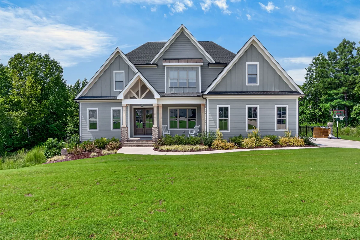 Front exterior of a gray Clayton home framed by mature trees and lawn