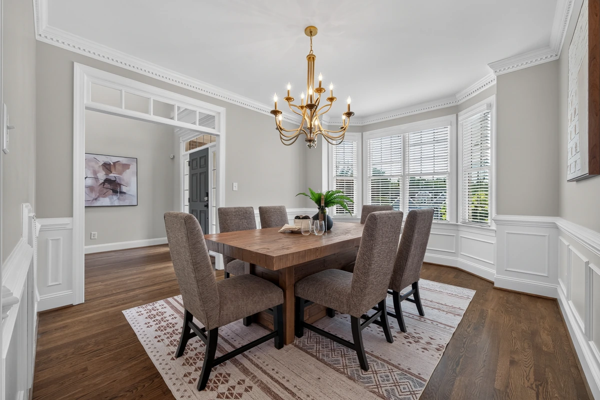 Formal dining room with a wood table, chandelier, detailed millwork, and bay windows