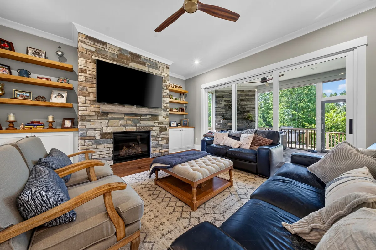 Furnished Clayton living room with stone fireplace and wooded views