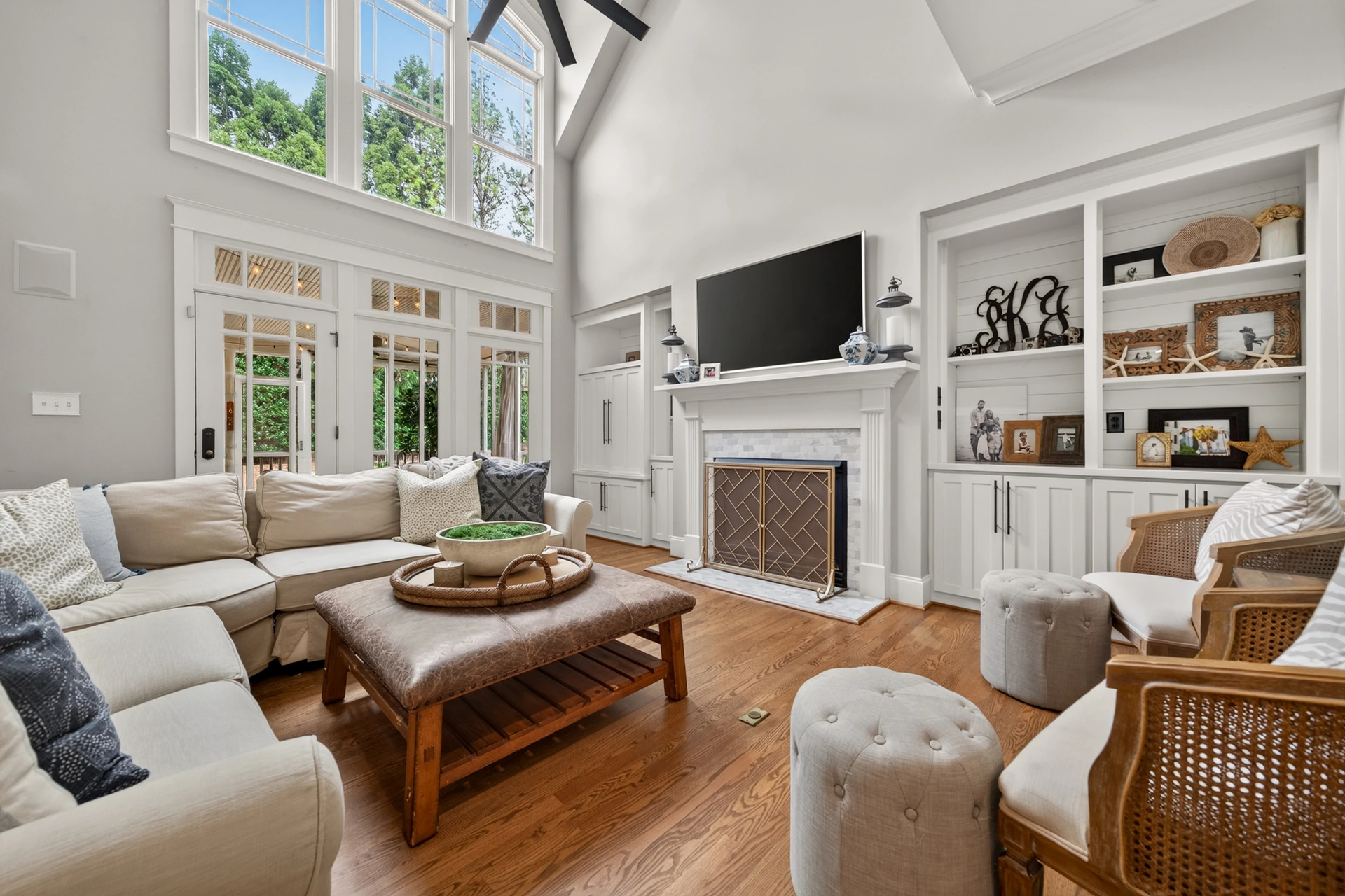 Bright living room with tall windows, built-in shelving, fireplace, and connected seating area