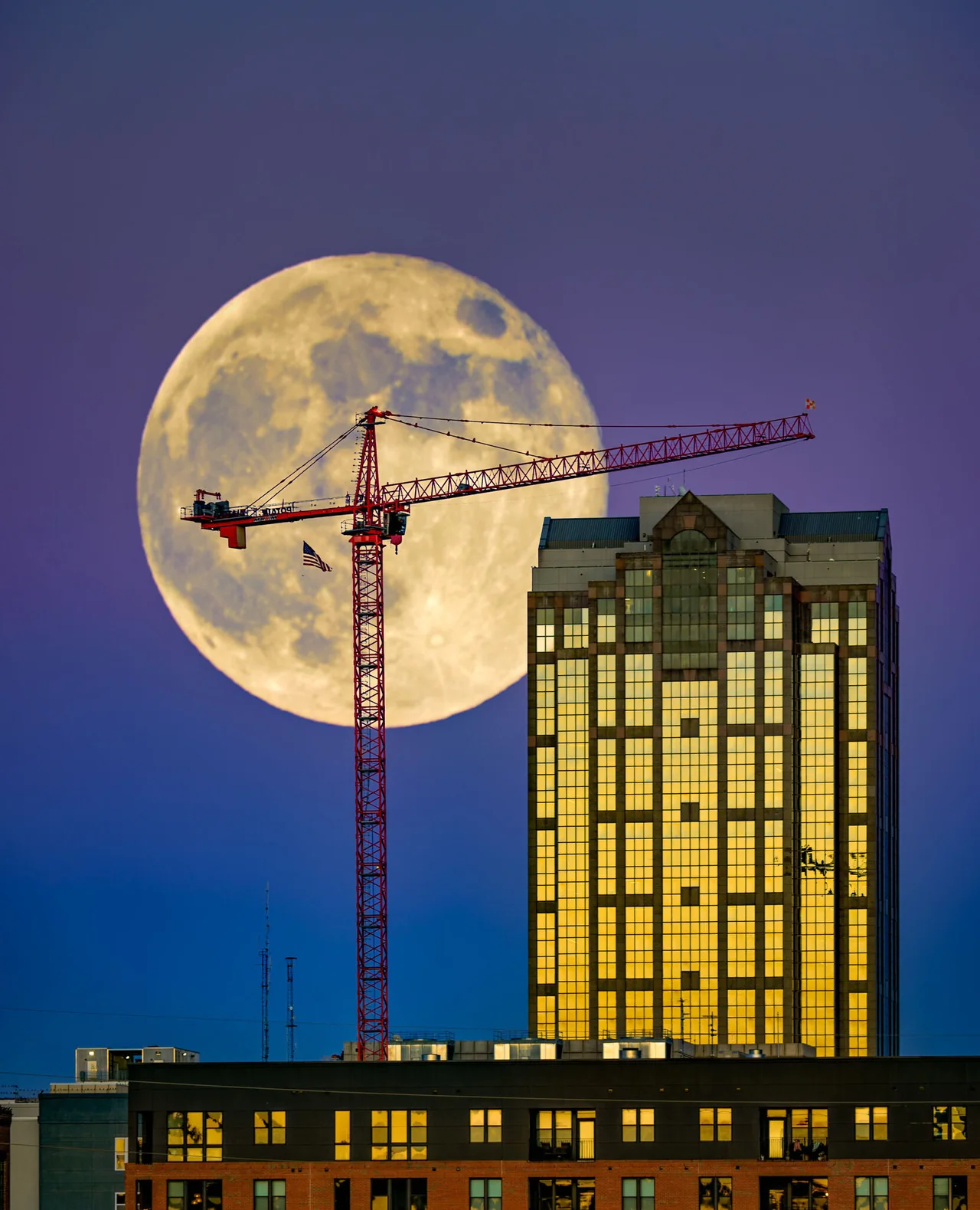 Moon behind a construction crane and an illuminated building in the RDU area