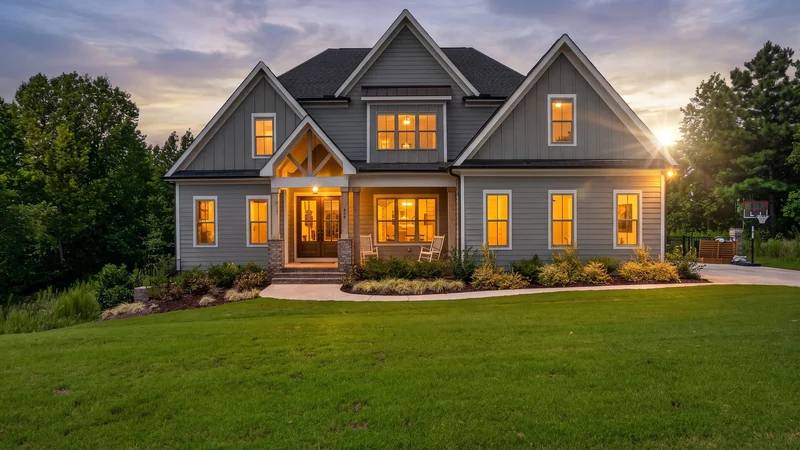 Twilight property presentation with illuminated windows and a pool.