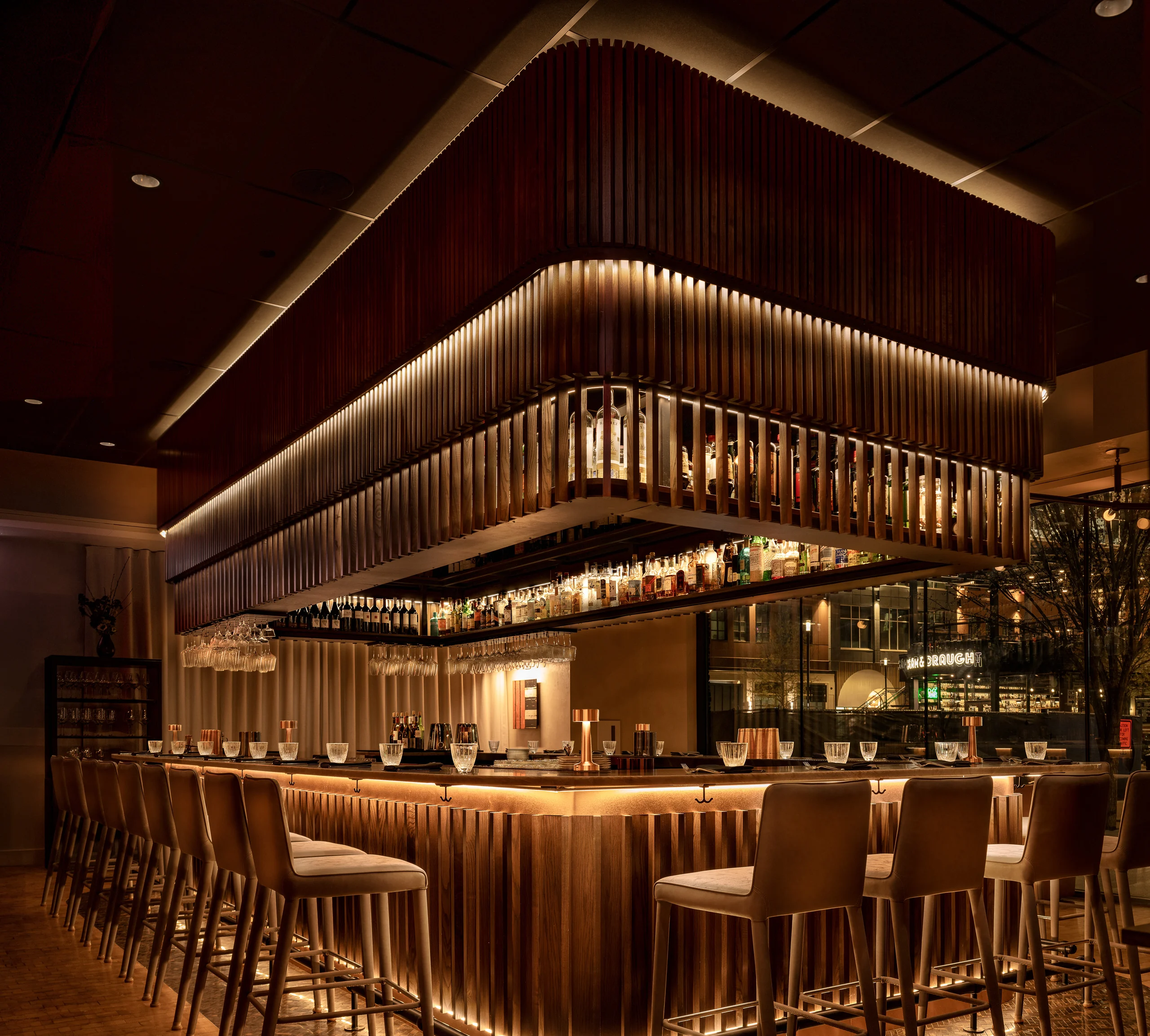 Illuminated hospitality bar with layered woodwork and a complete seating area
