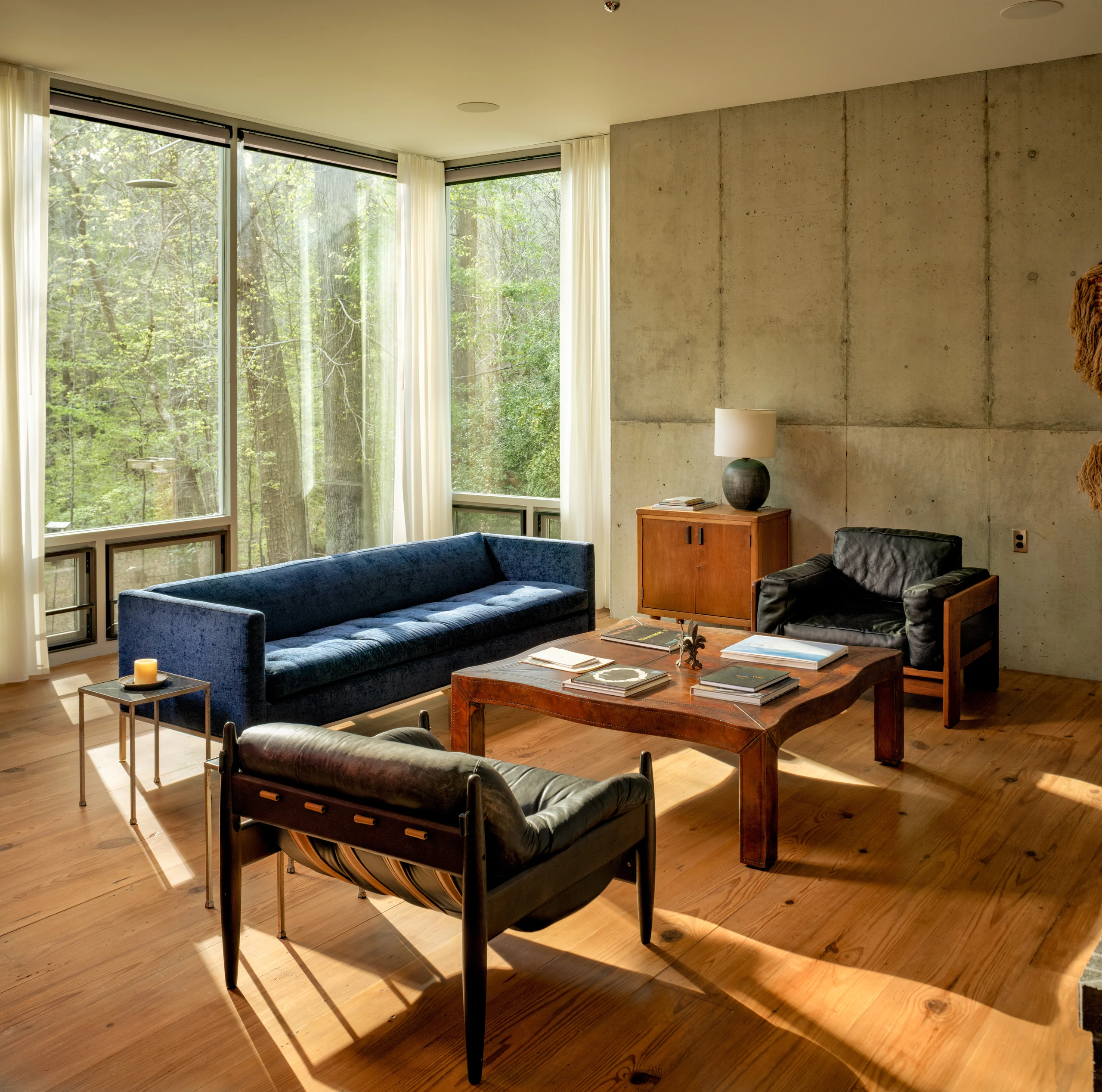 Furnished rental living space with concrete walls and wooded views